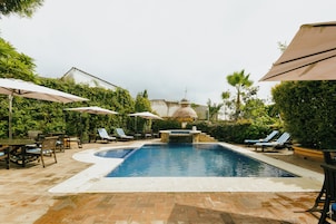 Una piscina al aire libre, sombrillas, sillones reclinables de piscina