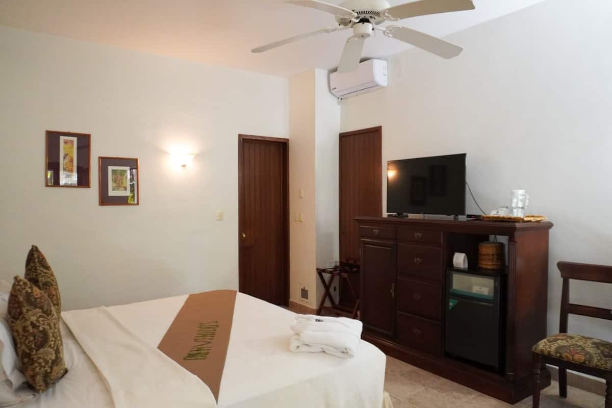Quarto de hotel com cama, televisão, escrivaninha e cadeira.
