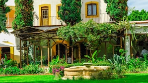 Un edificio con un patio techado, una fuente y abundante vegetación.
