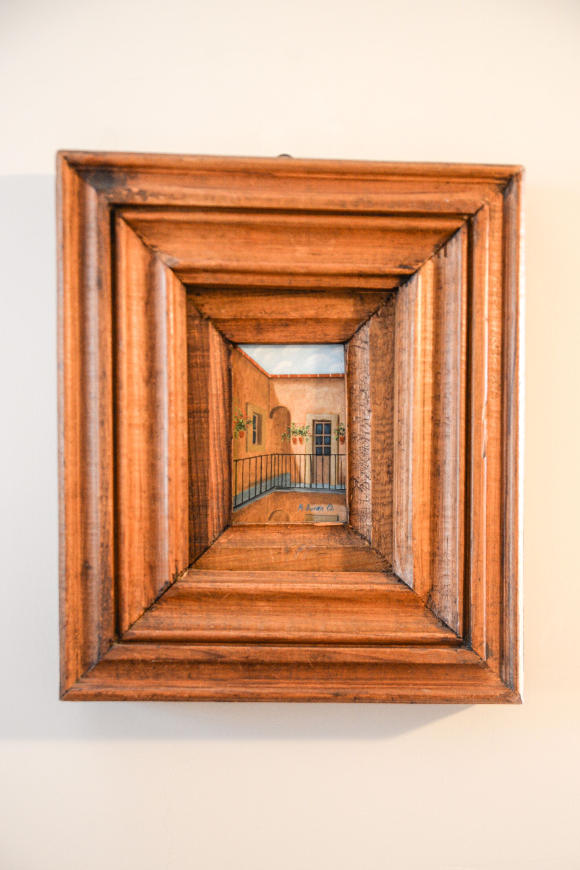 Un couloir en bois, avec une porte et des fenêtres, qui mène à une pièce dotée d’un balcon.