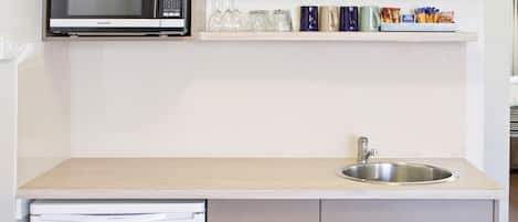 A compact kitchen with a microwave, sink, and a refrigerator.