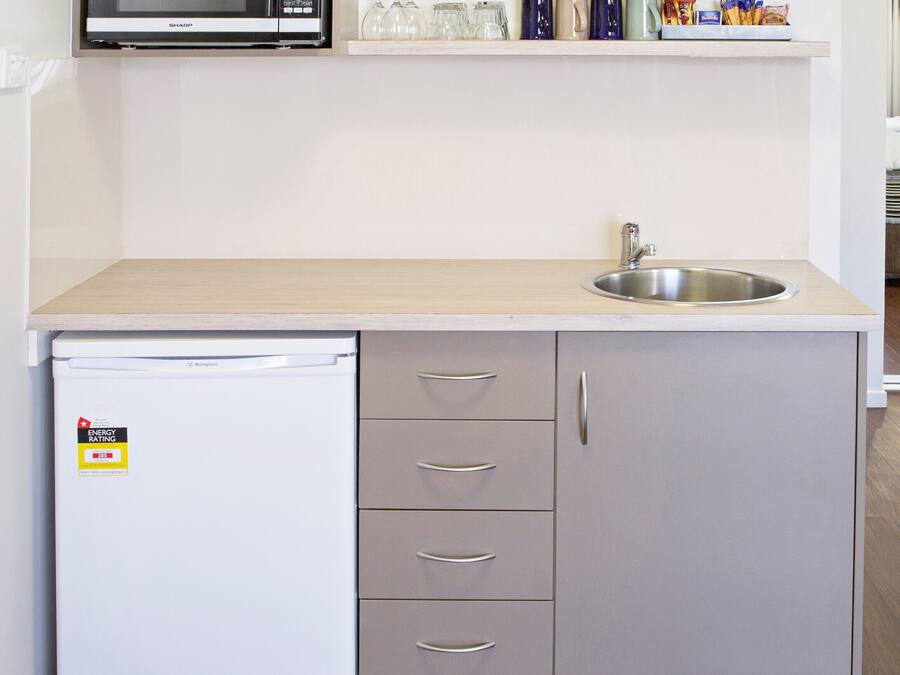 A compact kitchen with a microwave, sink, and a refrigerator.