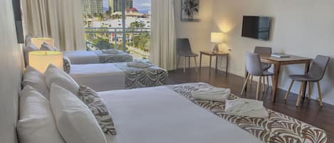 Une chambre d’hôtel avec deux lits, un bureau, des chaises, une télévision et une vue sur les bâtiments.