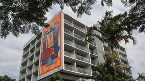 Un hotel moderno con varios pisos, balcones y un gran mural colorido en la fachada.