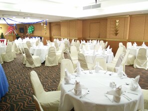 A banquet hall with round tables set for dining, covered with white tablecloths and white chair covers. - Tai Pan Hotel (Bangkok)