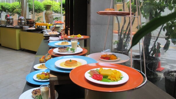 A buffet setup with various dishes on plates, a coffee station, and a decorative vase. - Tai Pan Hotel (Bangkok)