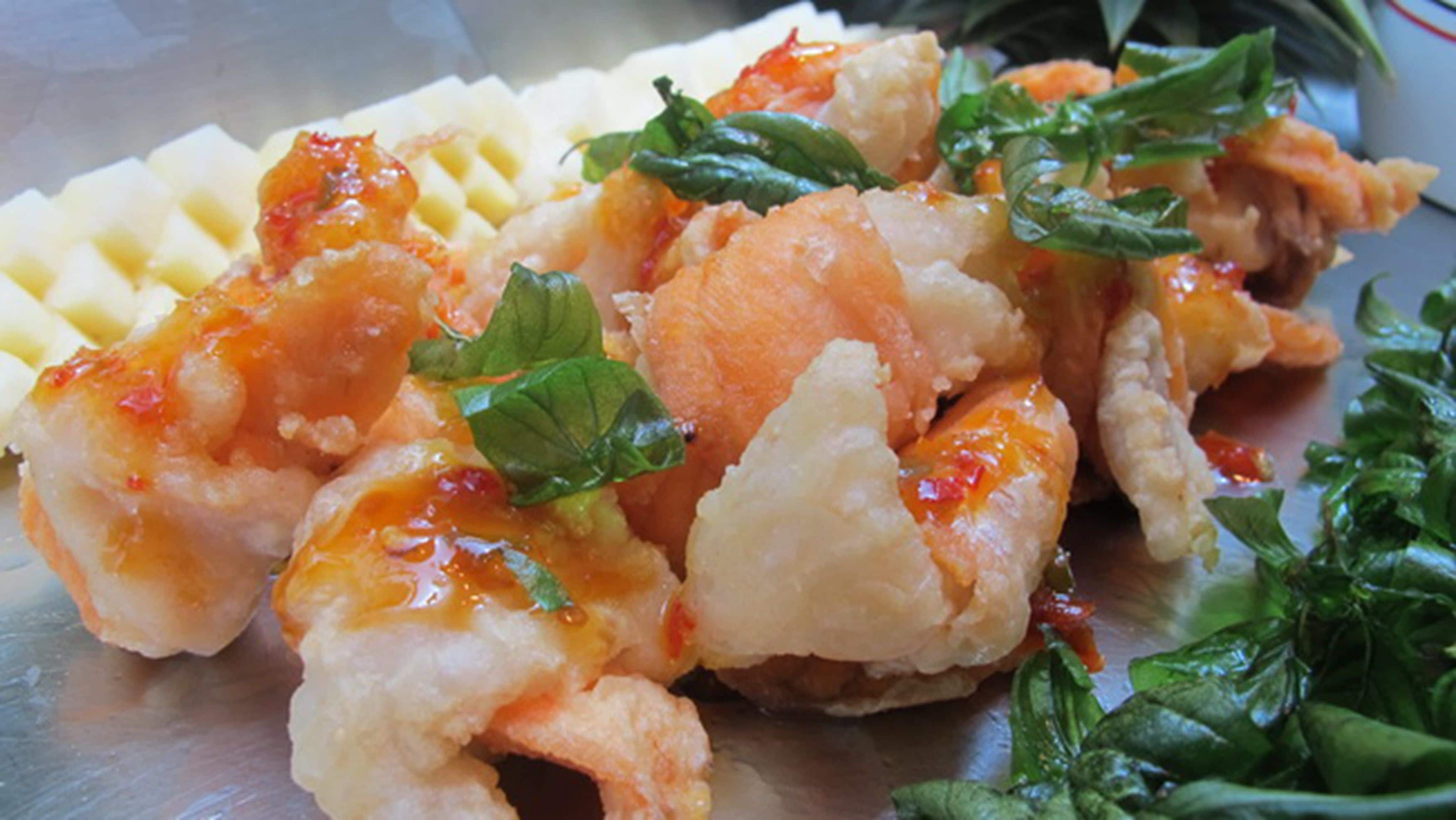 A close-up of a dish with shrimp and vegetables, possibly a seafood dish, garnished with herbs.