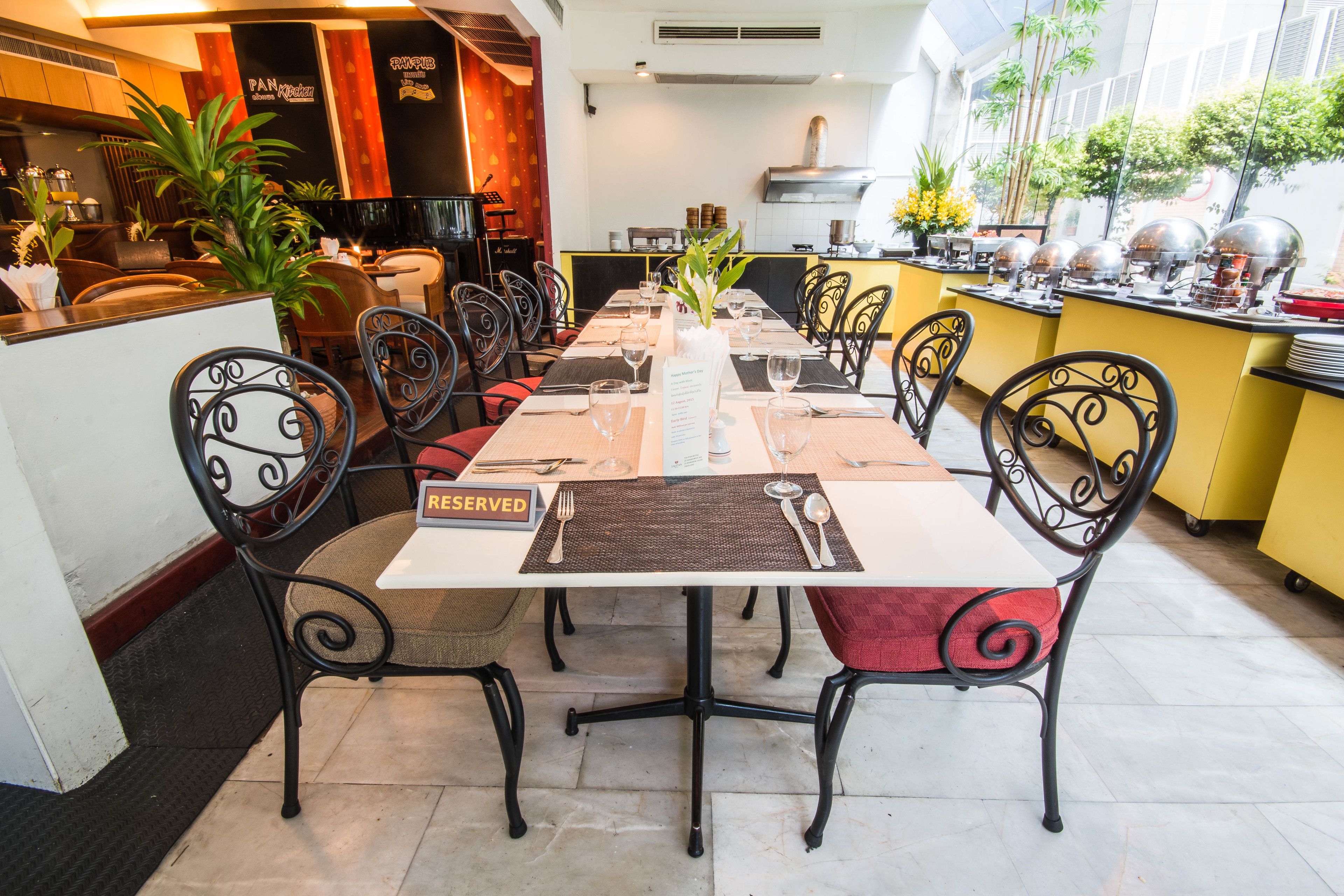 Restaurante com uma mesa comprida posta para refeição, rodeada por cadeiras e uma placa 'RESERVED' sobre a mesa.