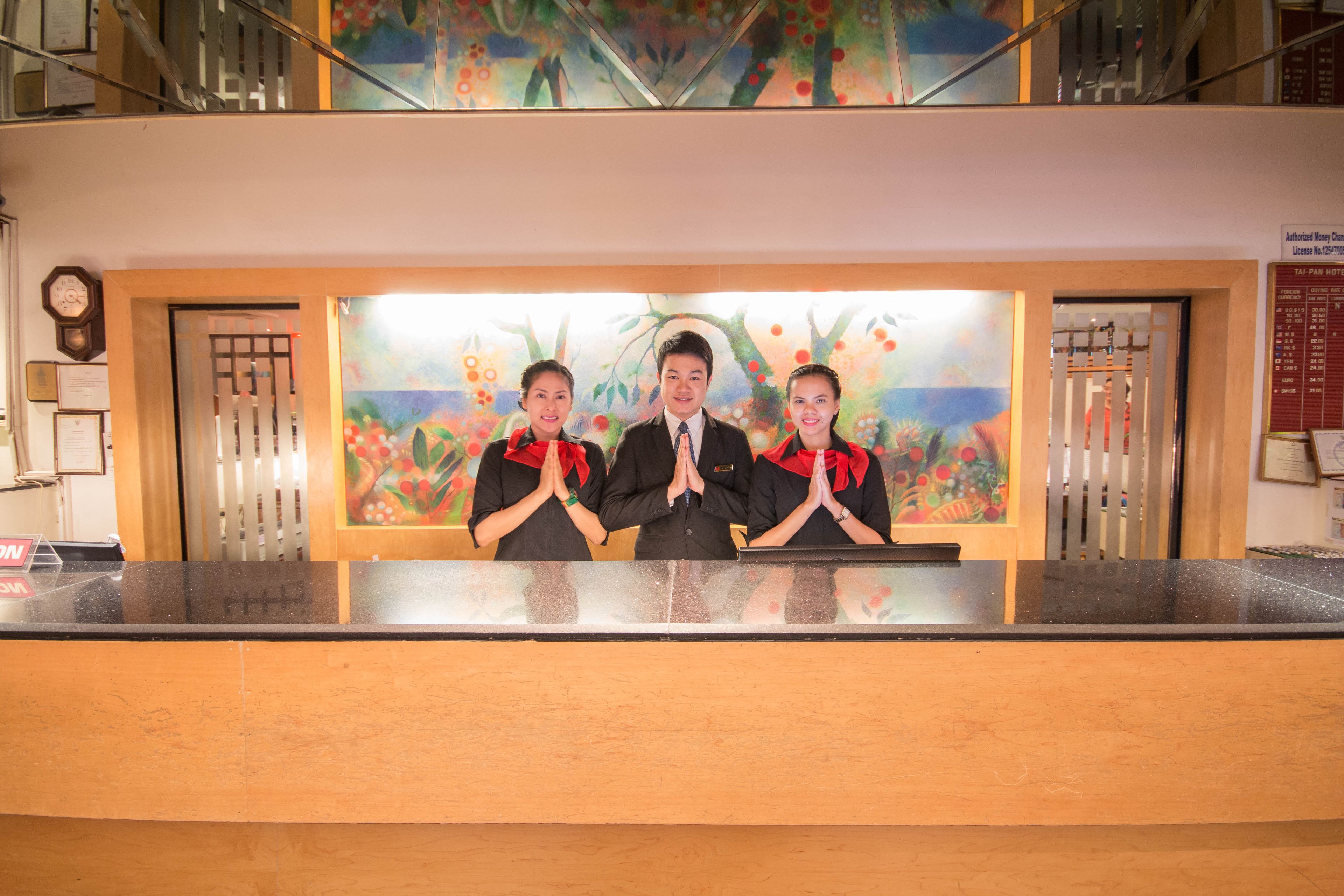 A reception desk with a painting of trees and flowers in the background.