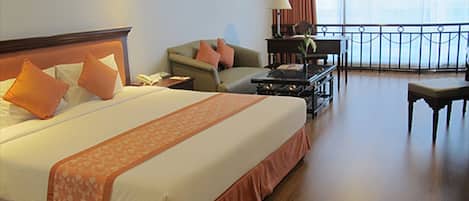 Een hotelkamer met een groot bed, een bank, een bureau en een balkon met een leuning.