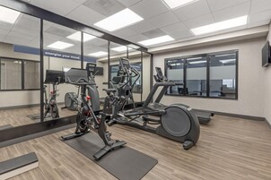 Un gimnasio con equipamiento de ejercicio, un espejo y un letrero motivacional.