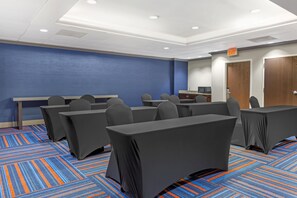 A conference room with tables and chairs, a blue accent wall, and an exit sign. - Hampton Inn Washington (Washington)