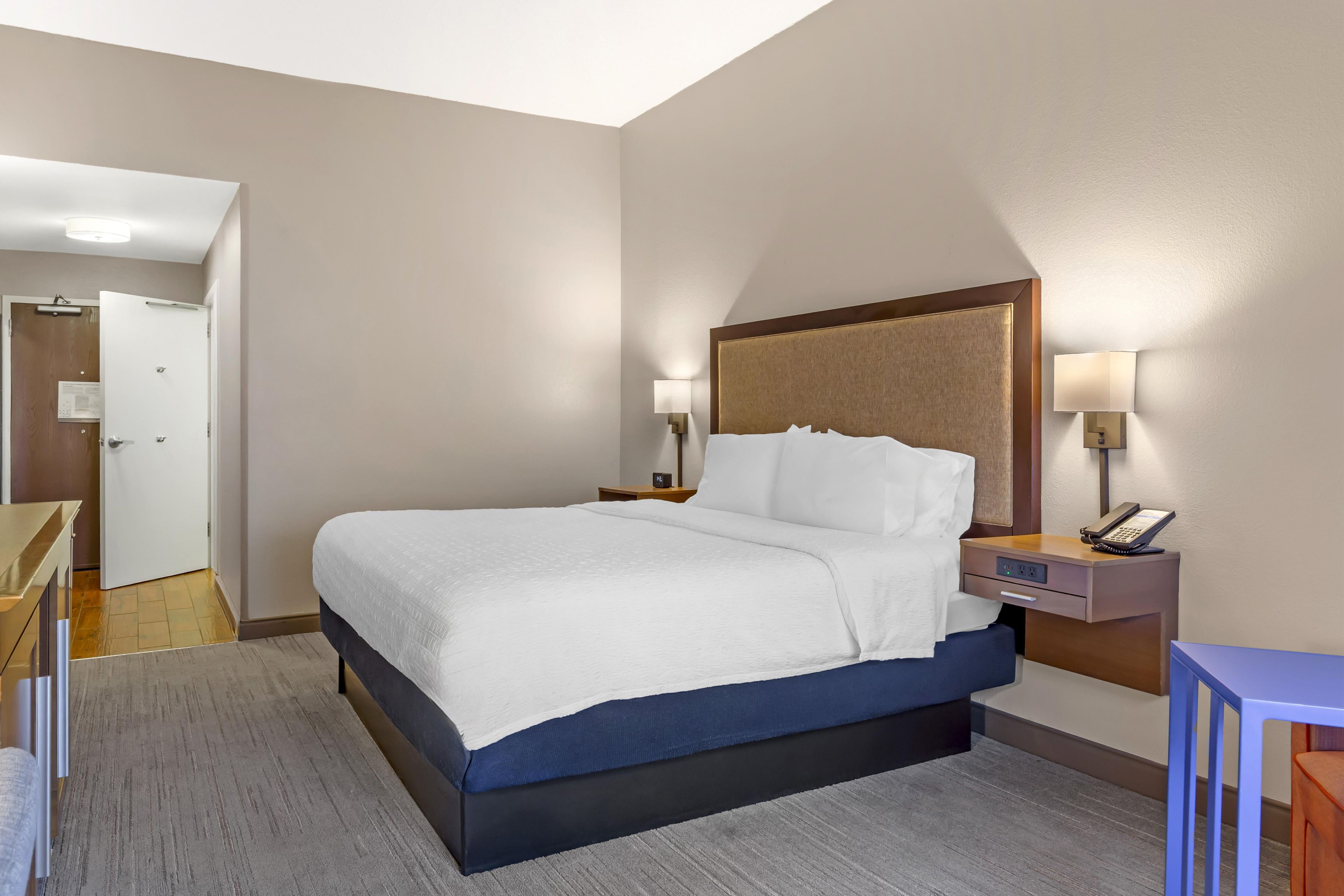 Ein Hotelzimmer mit einem Bett, Nachttischen, einem Schreibtisch und einem Sessel.