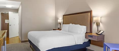 A hotel room with a bed, bedside tables, a desk, and a chair.