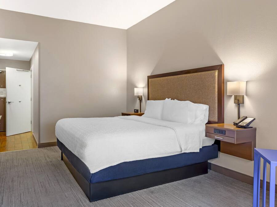 Una habitación de hotel con una cama, mesitas de noche, un escritorio y una silla.