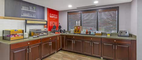 A breakfast area with a waffle station, a coffee machine, and a toaster.