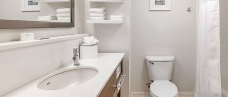 Et stilfuldt badeværelse med en hvid vask, toilet og bruseforhæng.