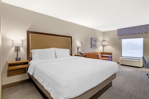 A hotel room with a large bed, bedside lamps, a desk, a chair, and a window with a view. - Hampton Inn Washington (Washington)