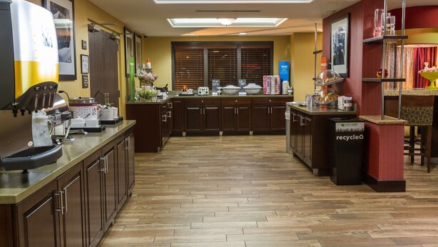 Una cocina de hotel con una isla central, una máquina de café y un contenedor de reciclaje.