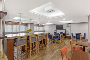 Una habitación de hotel moderna con una zona de bar, asientos y un televisor de pantalla plana.