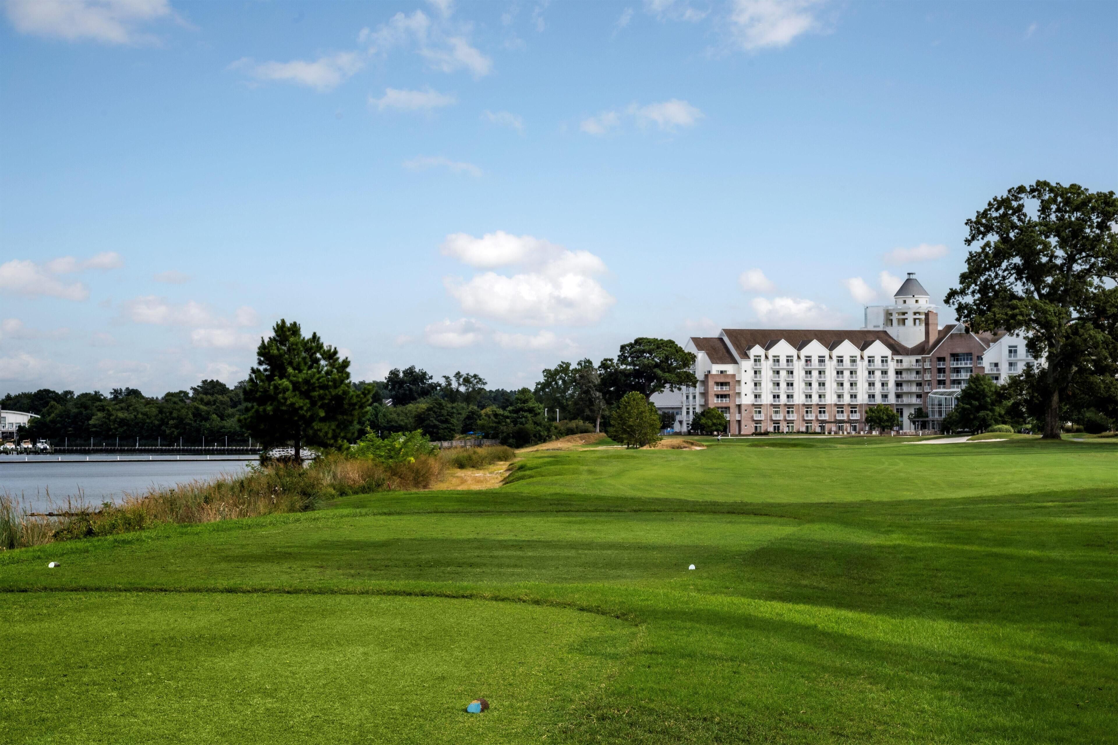 Un campo de golf con un edificio grande al fondo.