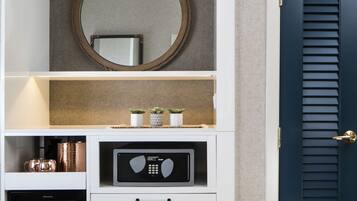 A white storage unit with a microwave, a small refrigerator, and a mirror above.