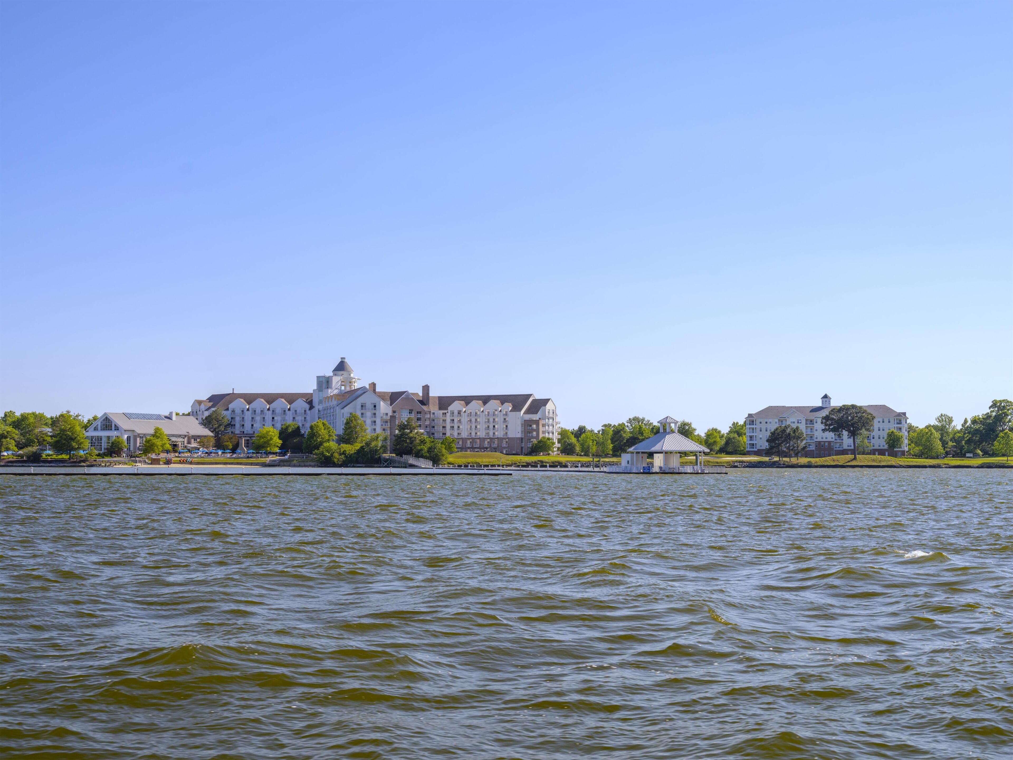 A waterfront property with a large building, a gazebo, and a body of water.