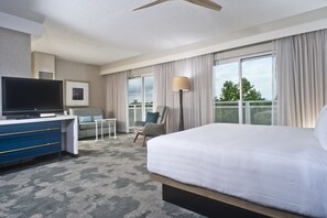 A hotel room with a large bed, a desk with a TV, a chair, and a view of the outdoors. - Hyatt Regency Chesapeake Bay (Cambridge)