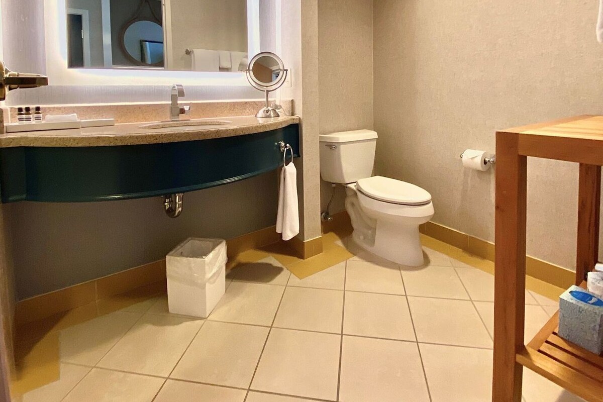 A bathroom with a large mirror, a toilet, a sink, and a wooden table.