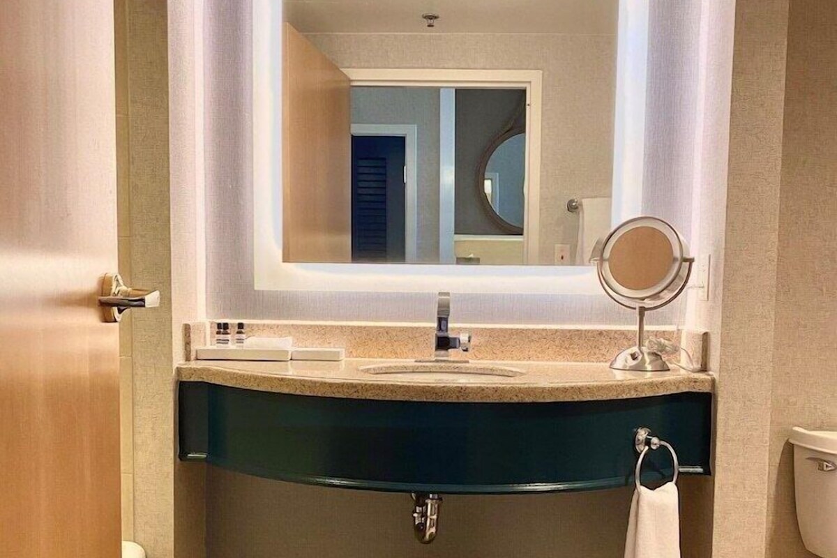 A bathroom with a vanity, mirror, sink, and toilet.
