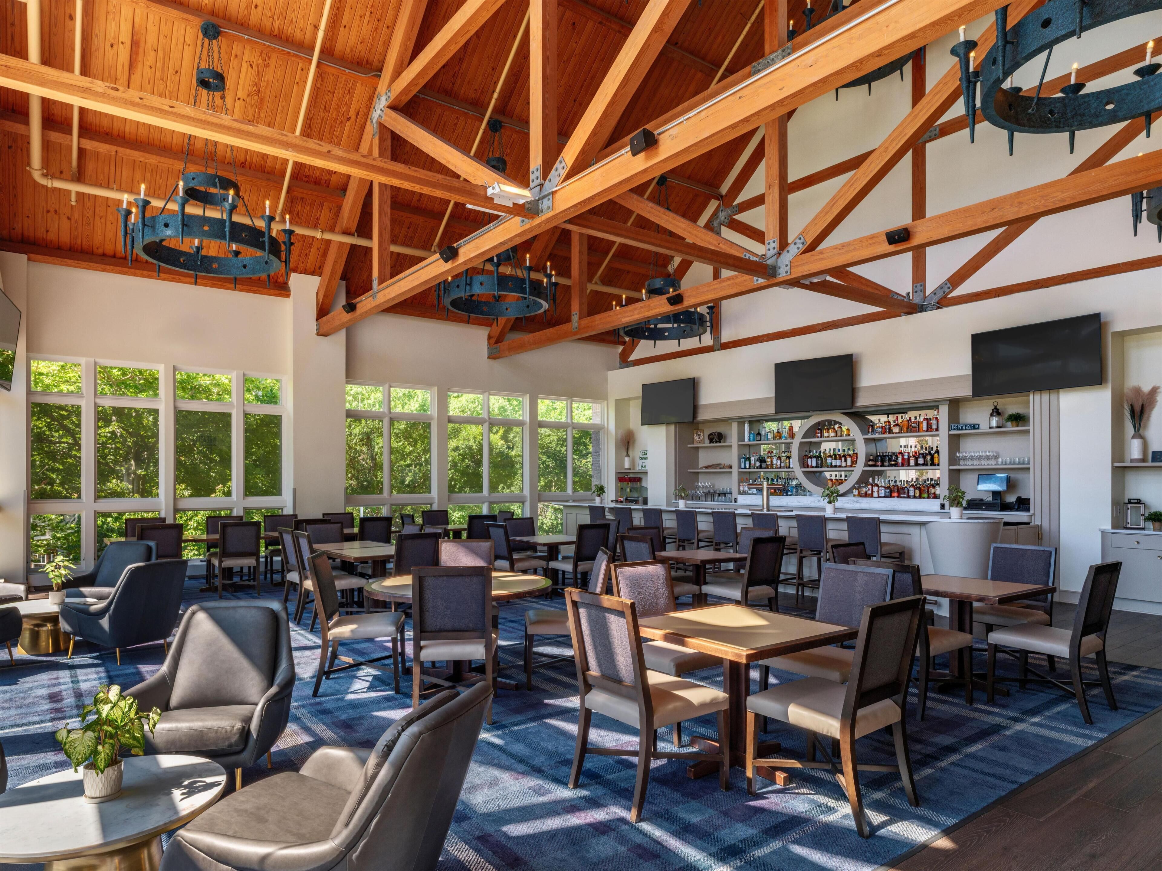 A spacious indoor area with high ceilings, wooden beams, and large windows allowing natural light.