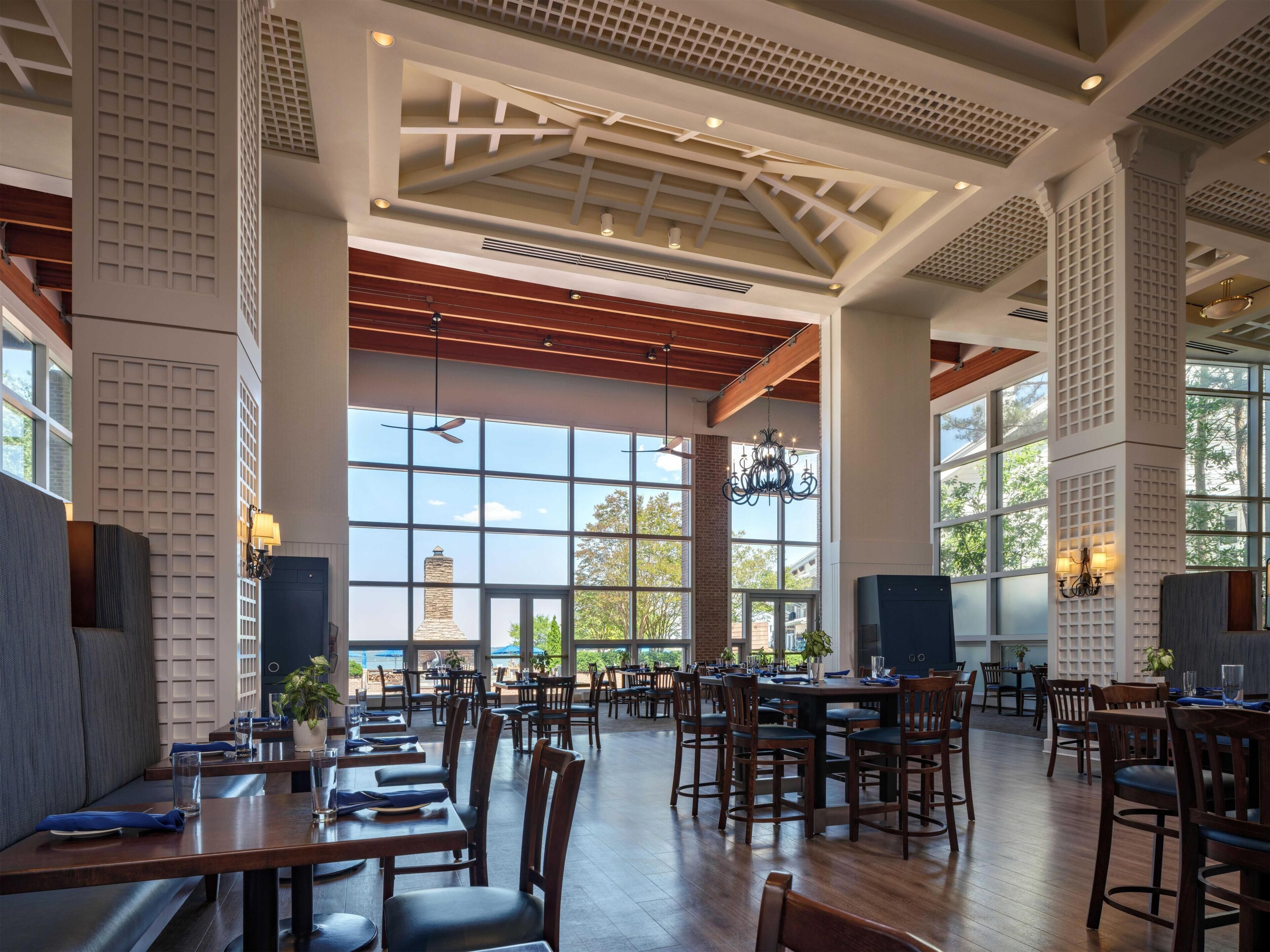 A spacious restaurant with high ceilings, large windows, and a variety of seating arrangements.