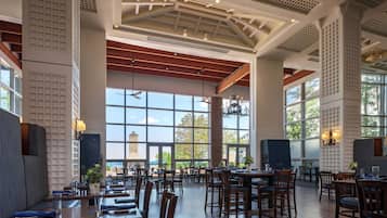 A spacious restaurant with high ceilings, large windows, and a variety of seating arrangements.