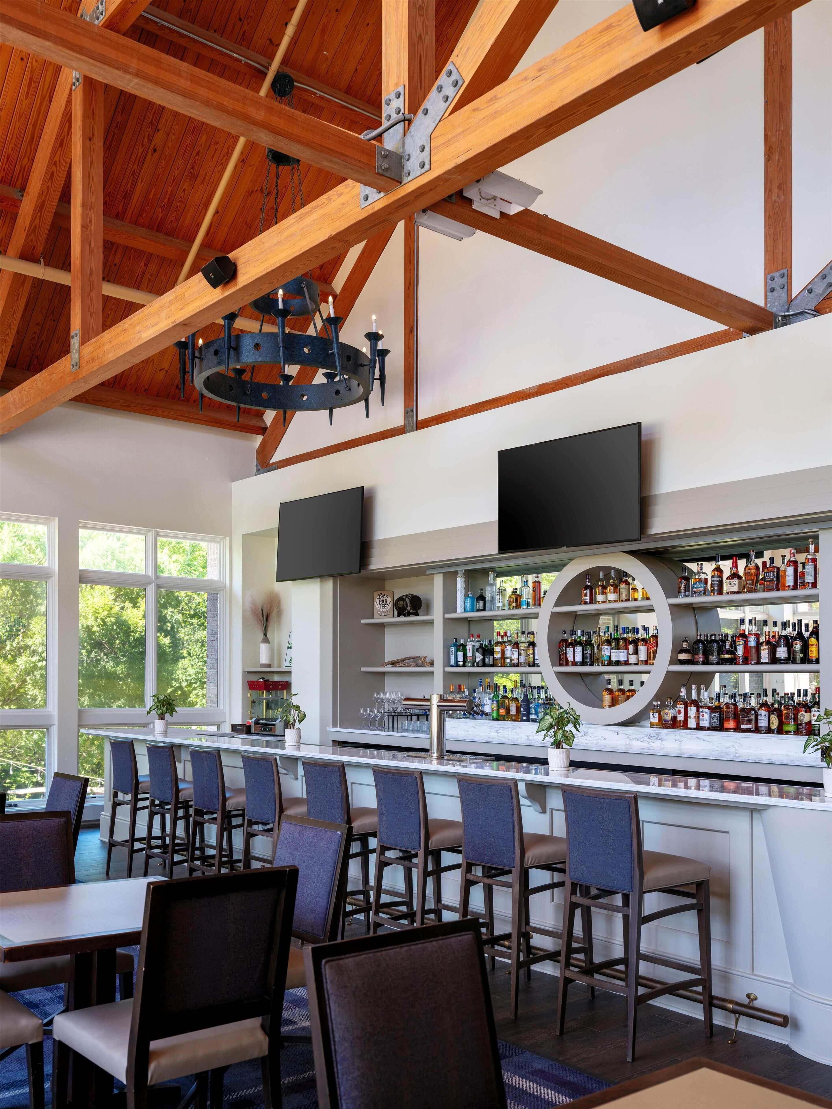 A bar area with a wooden ceiling, bar stools, and a liquor display.
