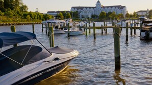 A marina with boats docked, a large building with a tower in the background, and a dock extending into the water. - Hyatt Regency Chesapeake Bay (Cambridge)