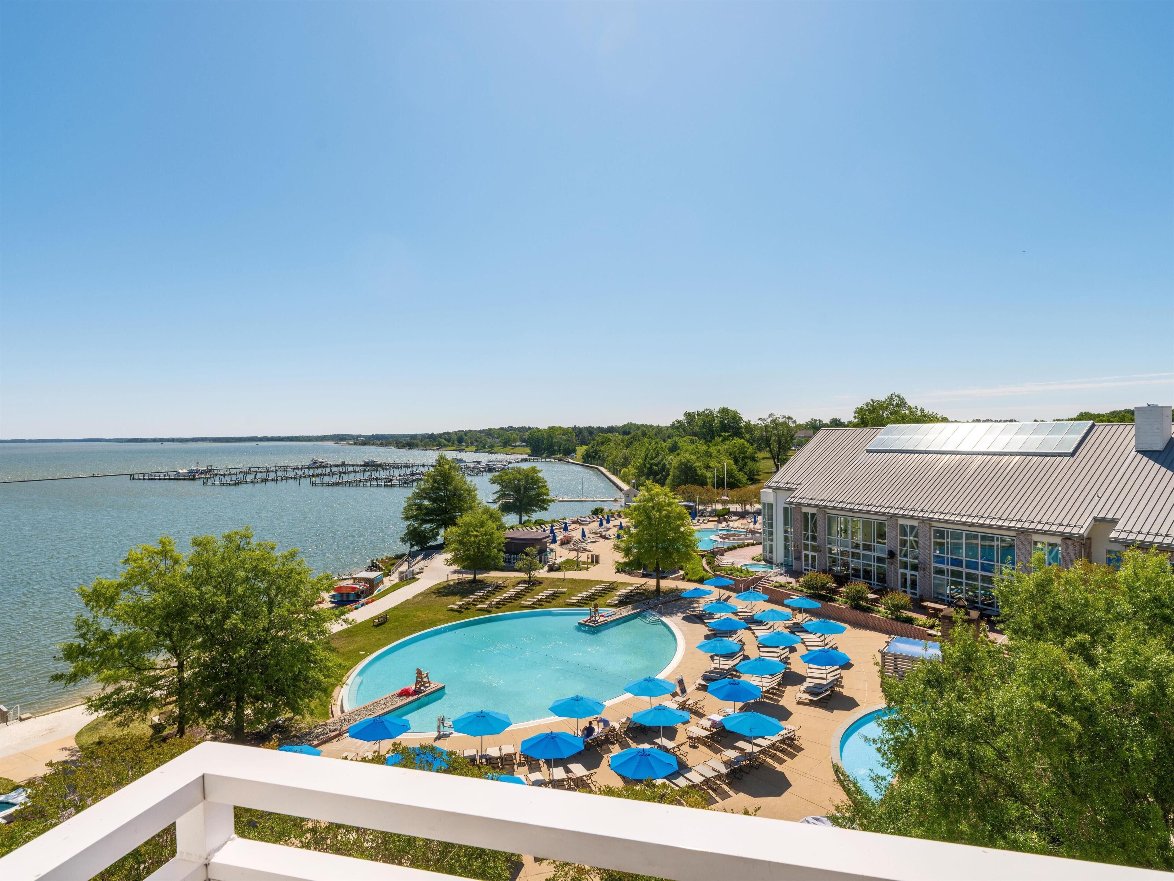 A resort with a large swimming pool, lounge chairs, and a view of the water.