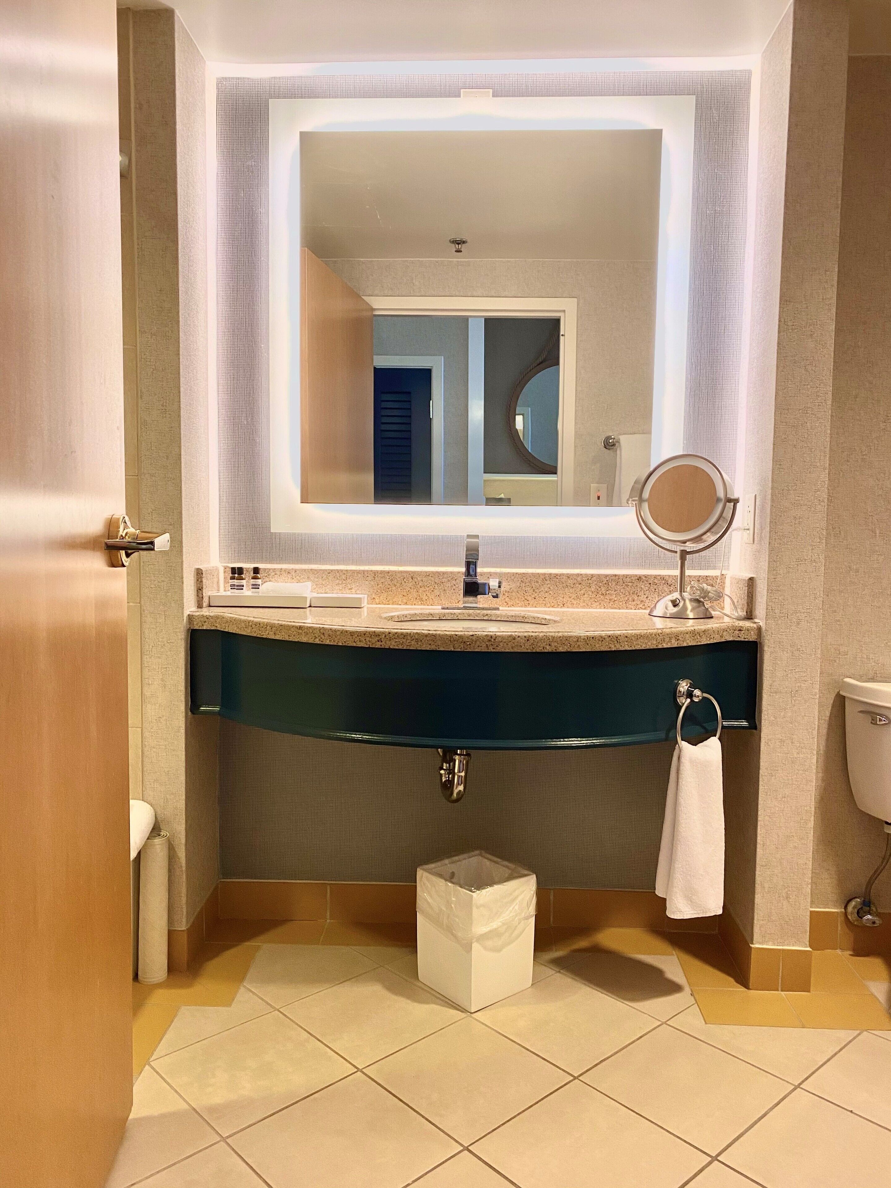 A bathroom with a large mirror, a sink, and a toilet.