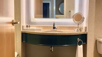 A bathroom with a large mirror, a sink, and a toilet.