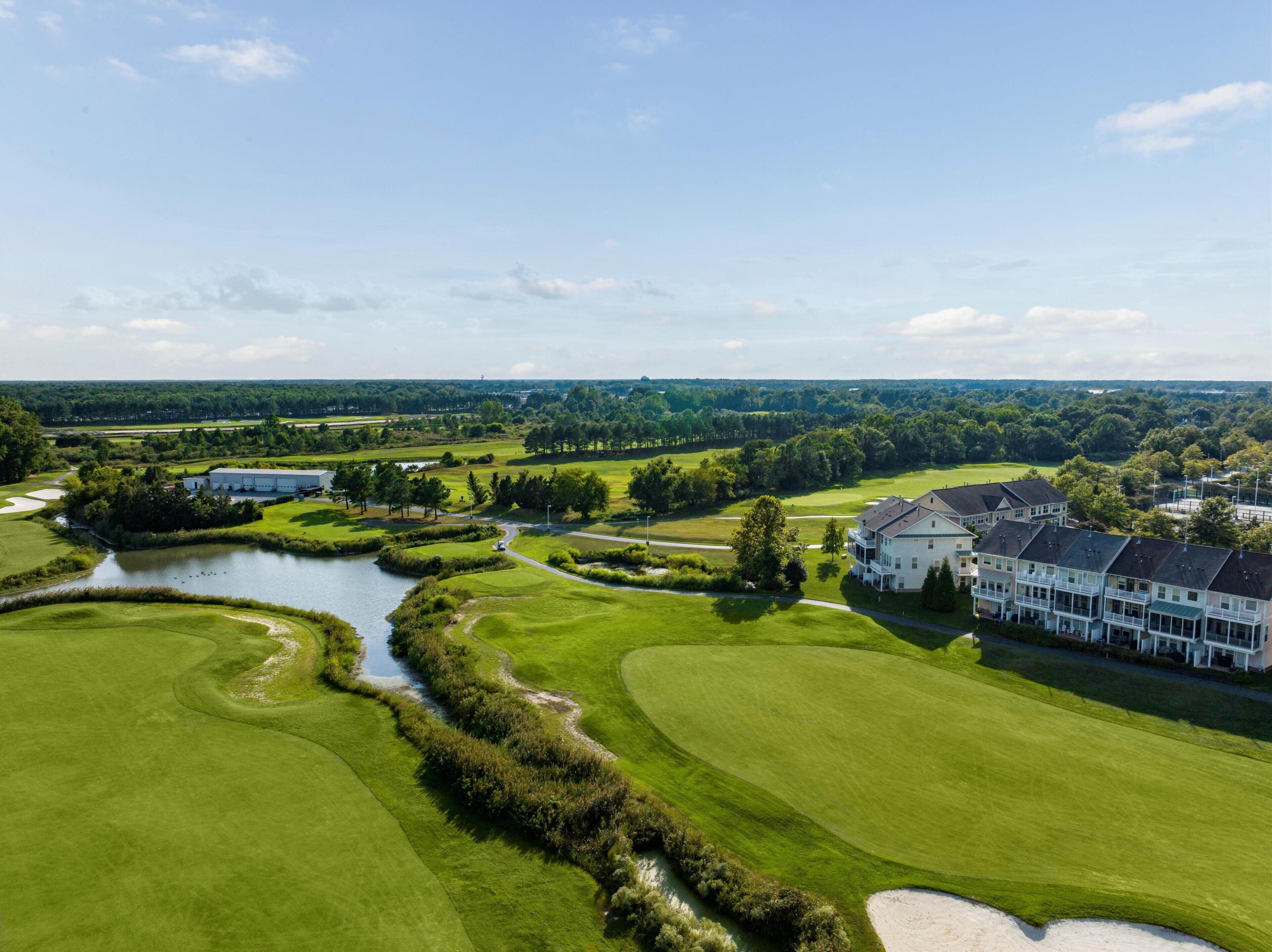 A golf course with a clubhouse and a large building with multiple windows.