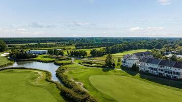 A golf course with a clubhouse and a large building with multiple windows.