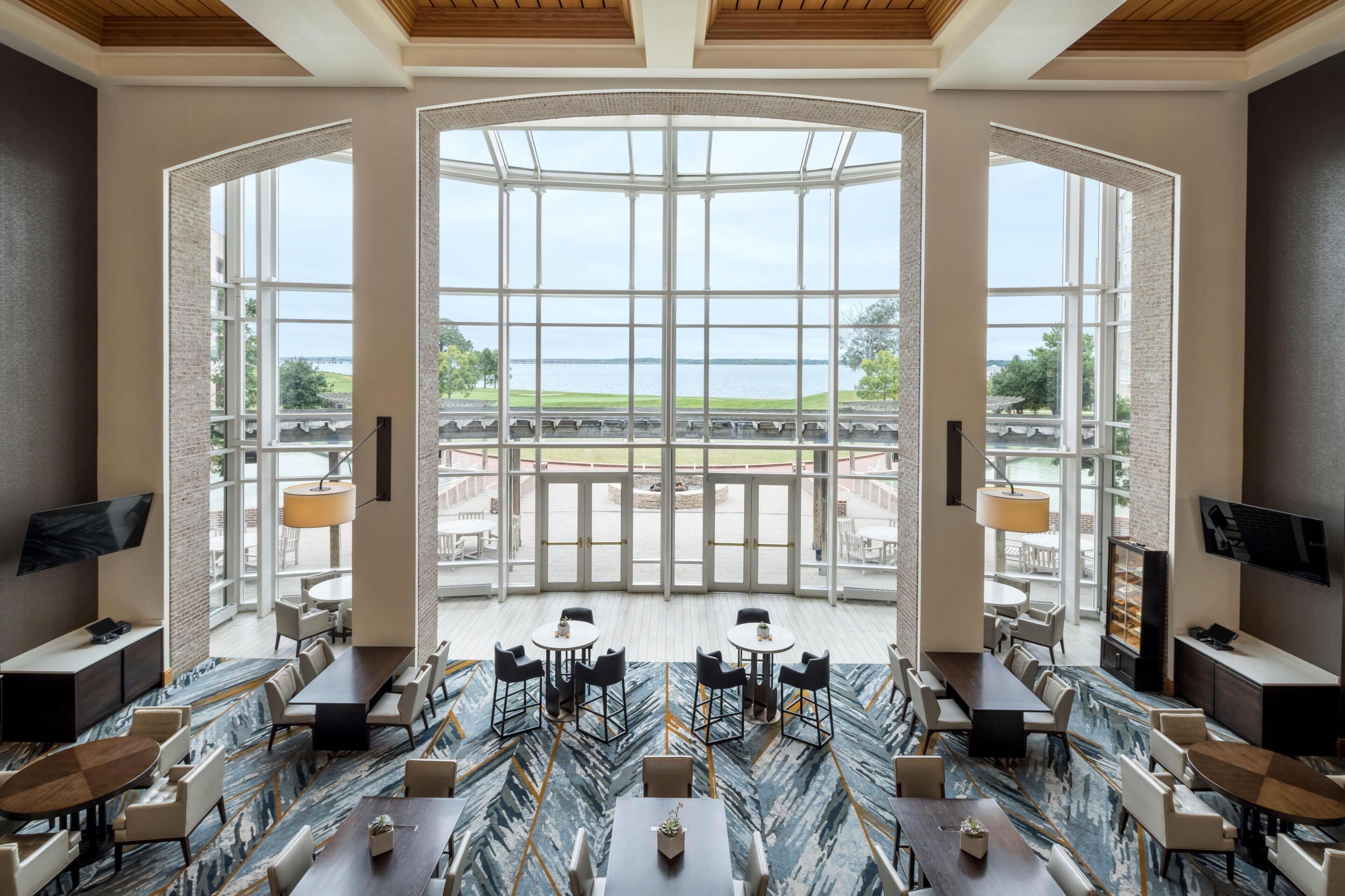 A spacious dining area with a view of the water, featuring a modern design with a marble floor and contemporary furniture.