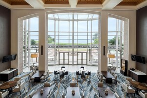 Un comedor amplio con vistas al agua, con un diseño moderno, piso de mármol y mobiliario contemporáneo.