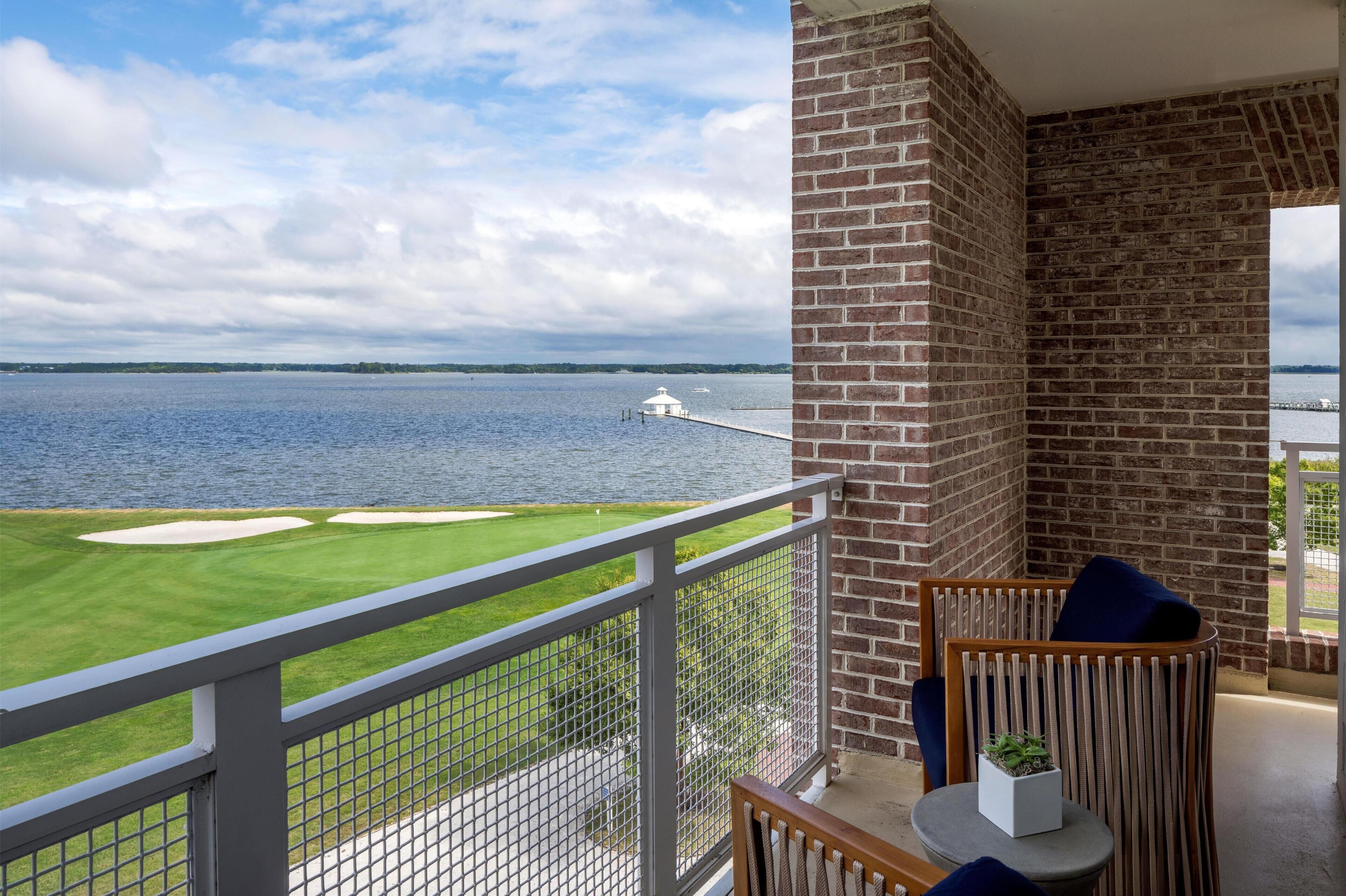 A balcony with a view of a golf course and a body of water.
