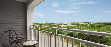 A balcony with a view of a beach and dunes.