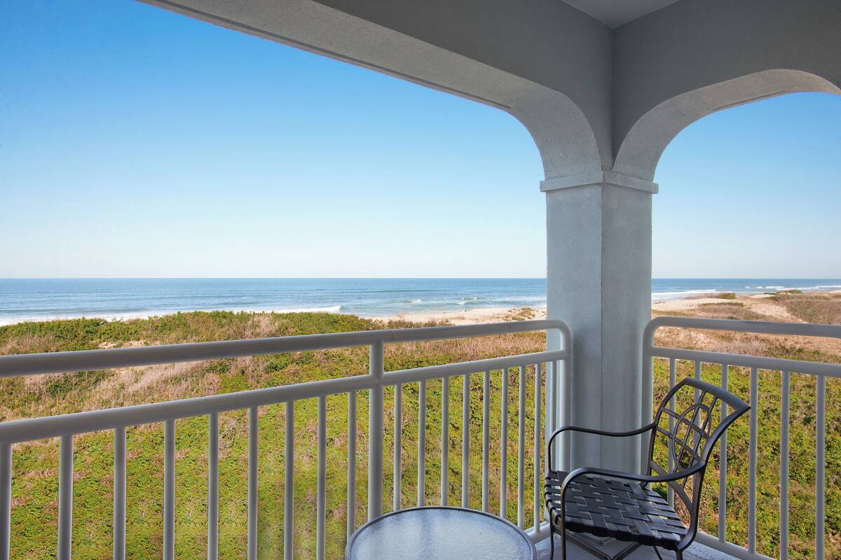A balcony with a view of the beach and ocean.