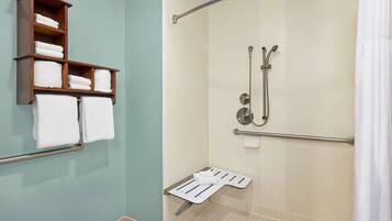 A bathroom with a wooden towel rack, a shower with a grab bar, and a white shower seat.