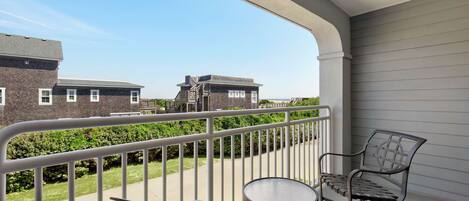 A balcony with a metal railing, a round table, and two chairs.