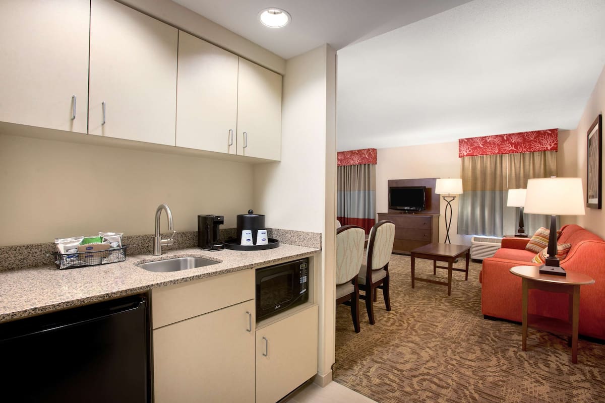 A compact hotel room with a kitchenette, a dining area, and a living space.