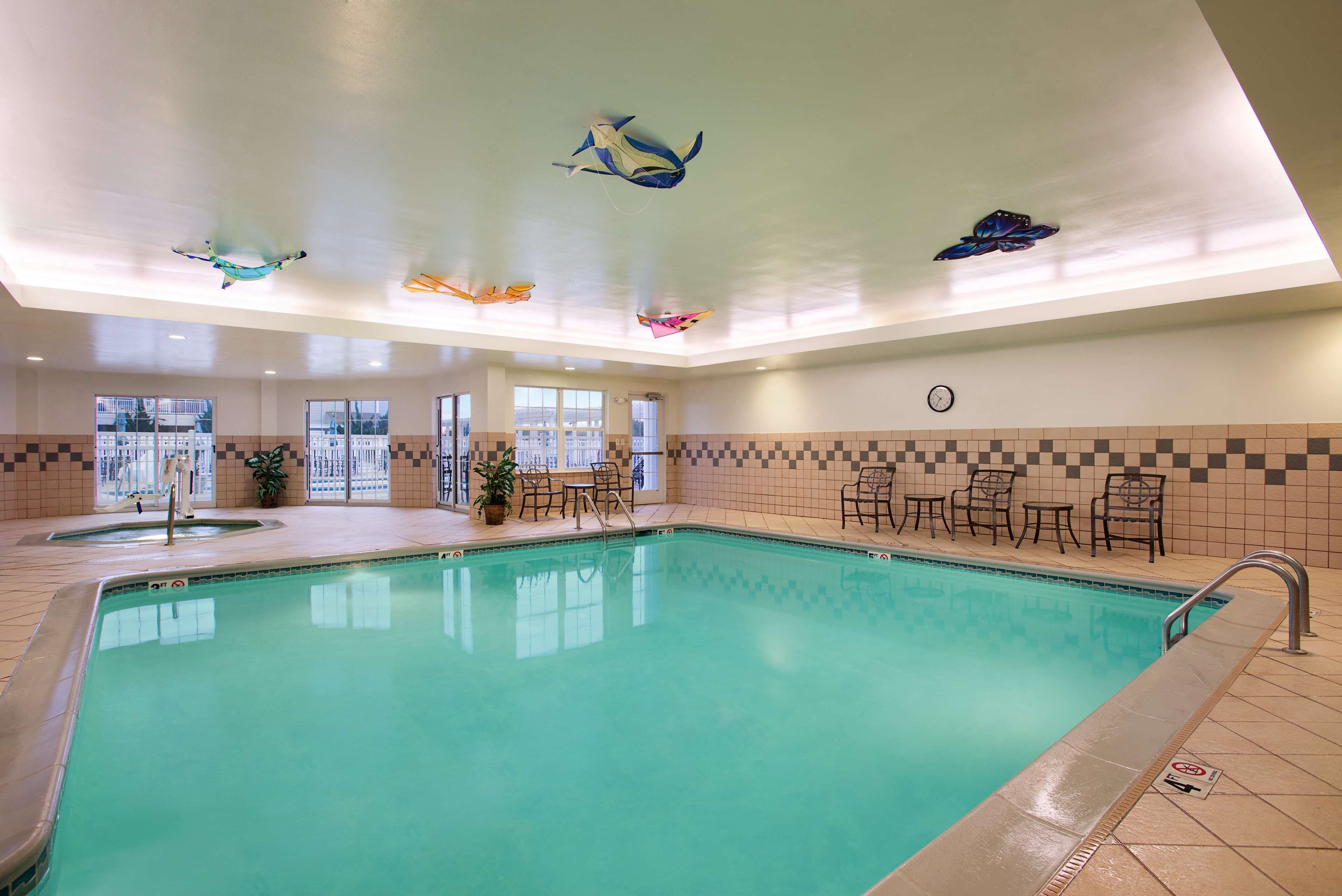 An indoor swimming pool with clear water, surrounded by tiled walls and a ceiling with decorative fish sculptures.