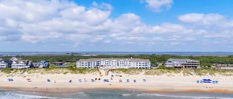 A beachfront hotel with multiple buildings, a sandy beach, and ocean waves.